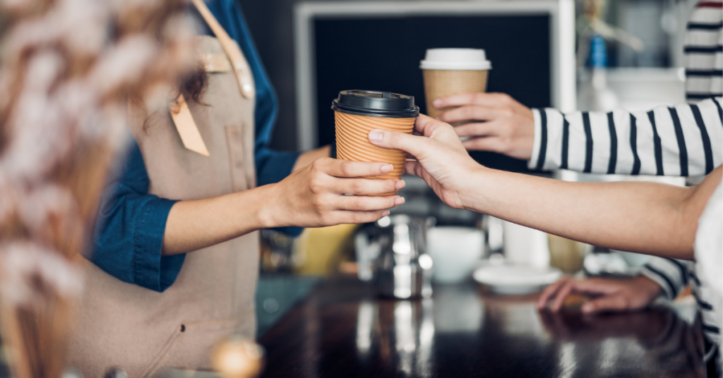 Image of Coffee being handed to customer from barista.